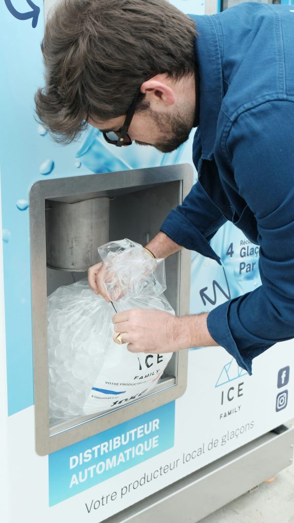 A man fills a bag with ice at a vending machine.