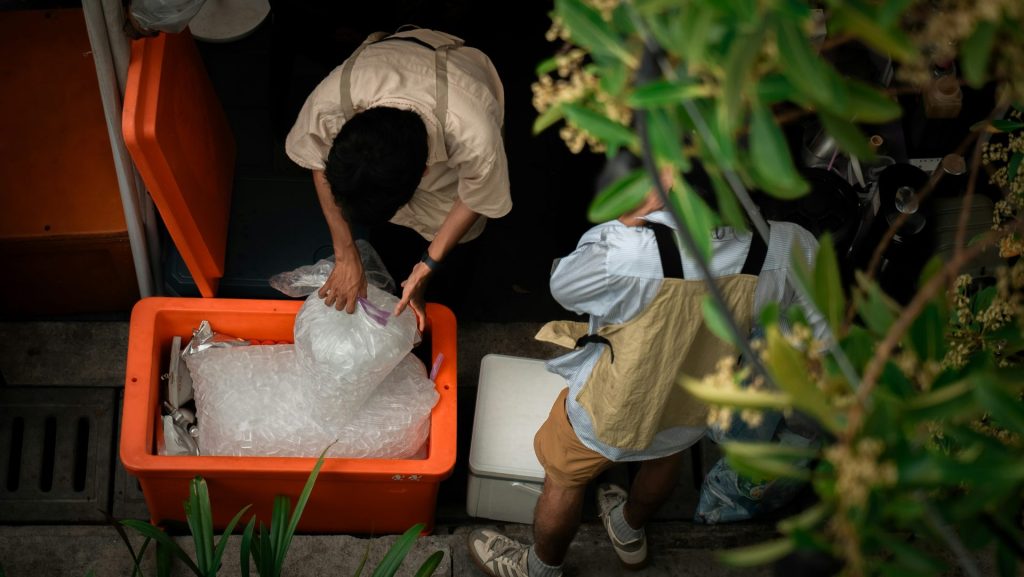 People packing fish into an orange cooler.