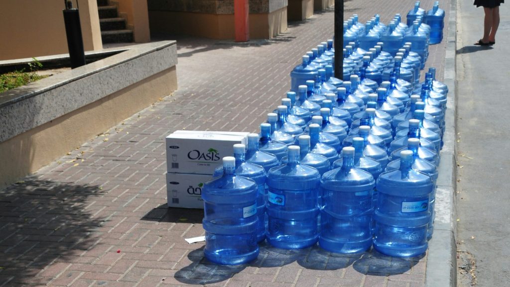 a row of blue water bottles sitting on the side of a road